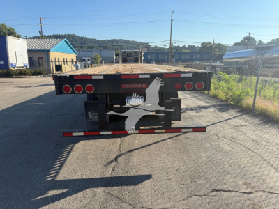 Rear view of Fontaine flatbed trailer showing Fontane logo and multiple taillights; visible license plate area and rear bumper with reflective tape.