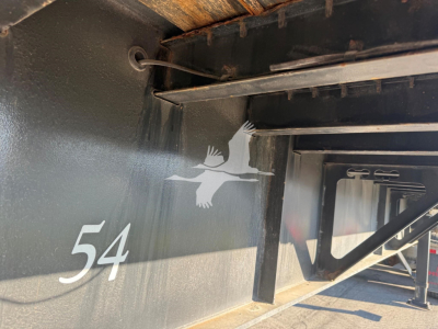 Trailer side with number 54 and Fontaine logo on black metal surface, showing part of the underframe and support beams.