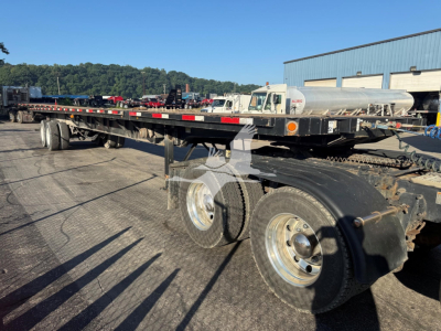Flatbed trailer showing dual rear axles and long deck with side rails, Fontaine XTP 4880SS2 trailer in a yard.