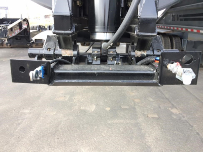 Dump trailer hitch/brackets and hydraulic components showing receiver bar and wiring mounts under a new trailer. Visible metal frame, hoses, and fittings.