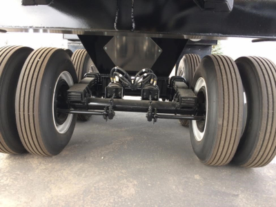 Trailer undercarriage showing dual axles with heavy-duty suspension and multiple wheels for a dump trailer