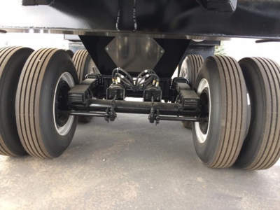 Trailer undercarriage showing tandem axles and dual wheeled suspensions for a dump trailer.