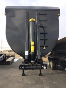 Dump trailer hitch system viewed from rear showing hydraulic cylinder and frame components.
