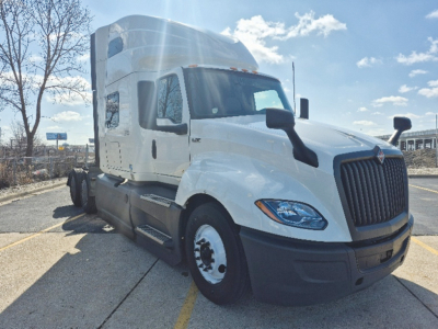 International LT625 highway sleeper truck in white, front-left view with cab, grille, headlights, and side mirrors visible.
