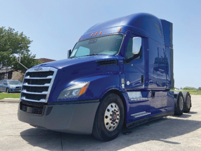 Truck cab showing blue 2022 Freightliner Cascadia126 conventional sleeper with chrome grille and side mirrors.