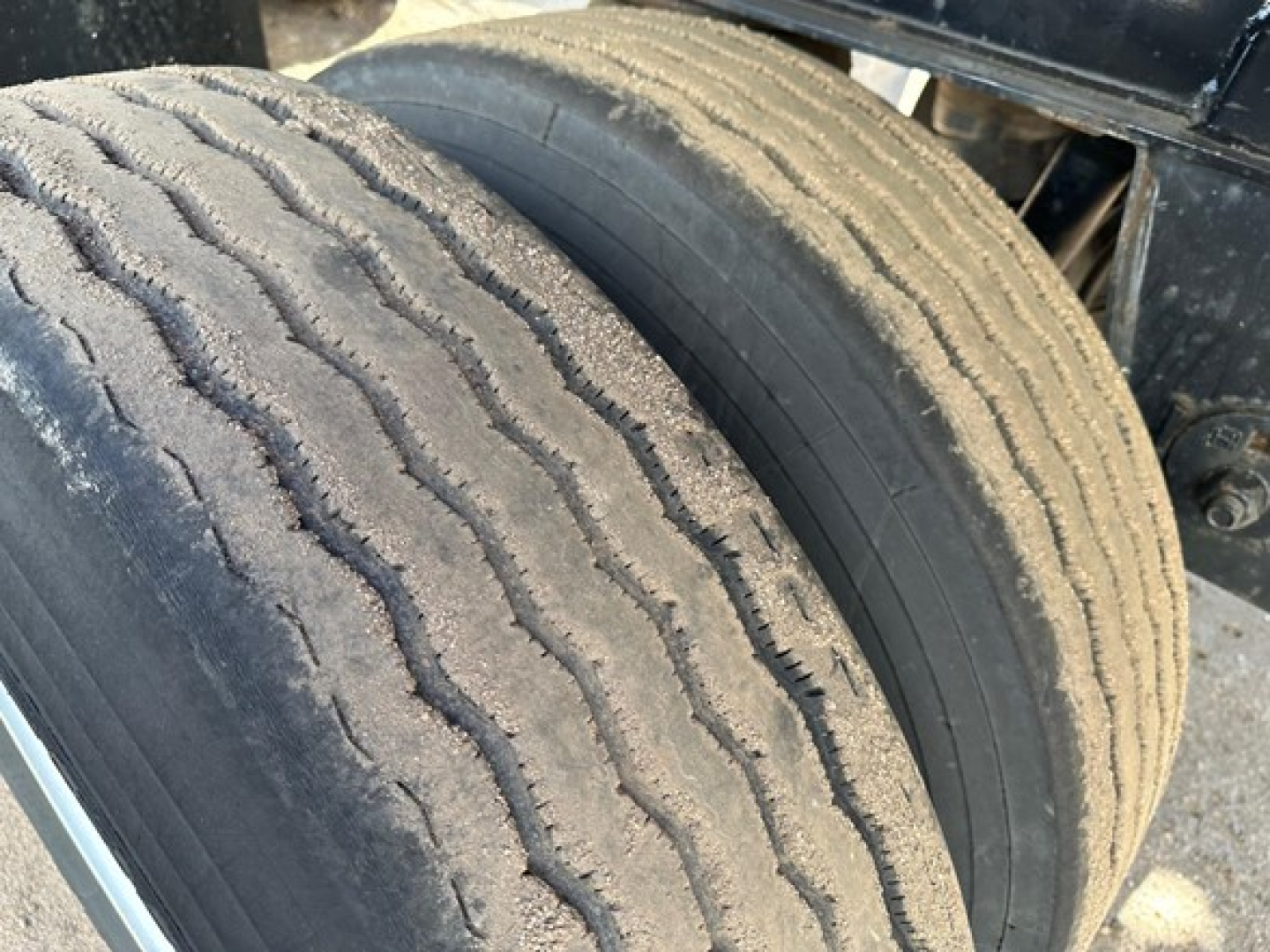 Tandem axle trailer wheel close-up showing worn tread and dual tires; part of Fontaine spread air combo flatbed trailer.