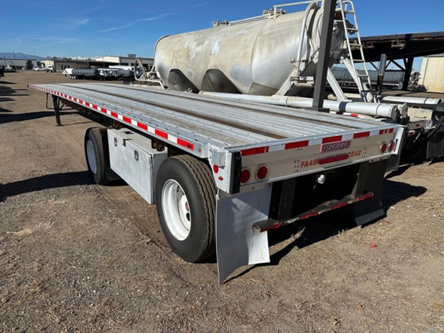 Trailer side view showing Fontaine spread air combo flatbed with dual rear axles and reflective safety tape