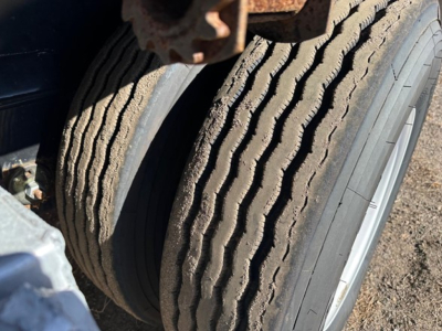 Axle with dual tires on Fontaine spread air combo flatbed trailer showing rugged tread and sidewall detail.