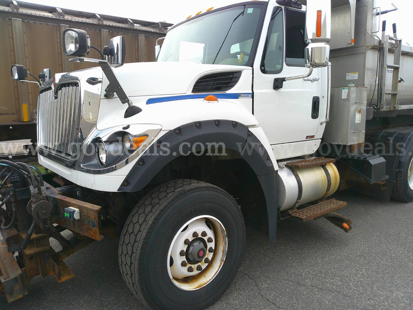Truck side view showing 2013 International WorkStar 7600 plow truck with front fender, large wheel, and plow mount.