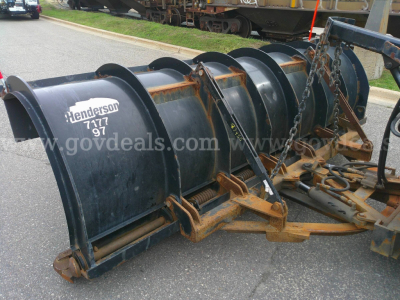 Snow plow blade attachment for a heavy truck with the text 'Henderson 7177 97' on the curved blade. Chain and mounting hardware visible; rust-colored support frames and black blade sections.