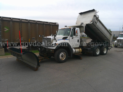 International WorkStar 7600 dump truck with front plow and raised dump bed, side view showing snow plow attachment and equipment