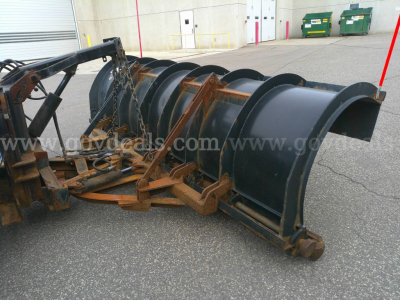 Snowplow attachment for a 2013 International WorkStar 7600 showing large metal blade and mounting frame in a parking lot.