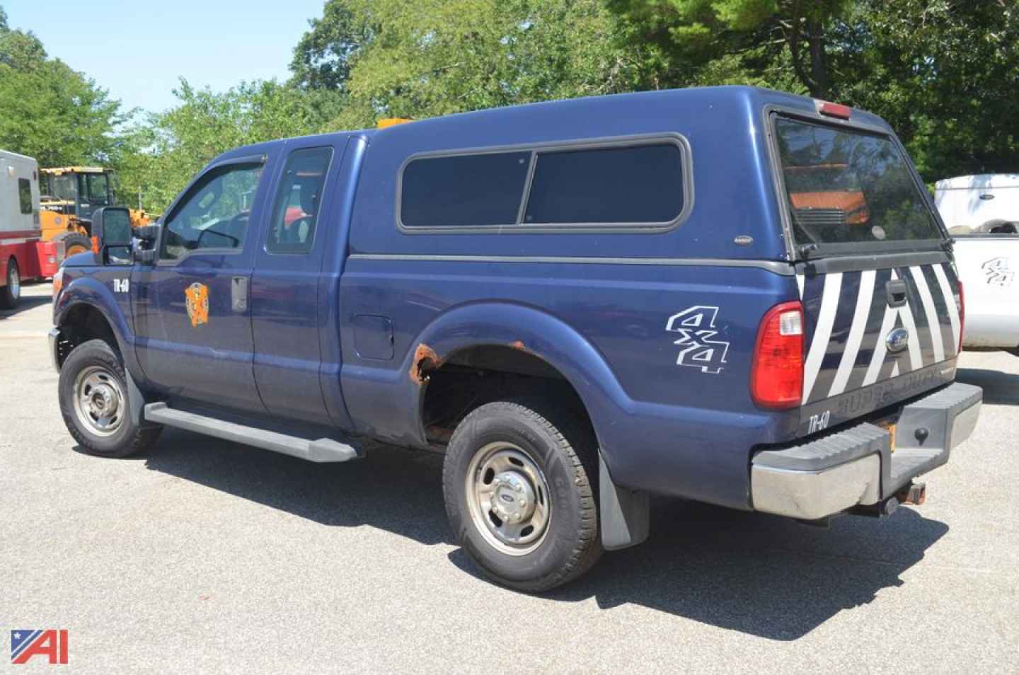 Ford F-250 Super Duty pickup truck with blue crew cab cap and white stripes on tailgate, side view showing 4x4 decal.