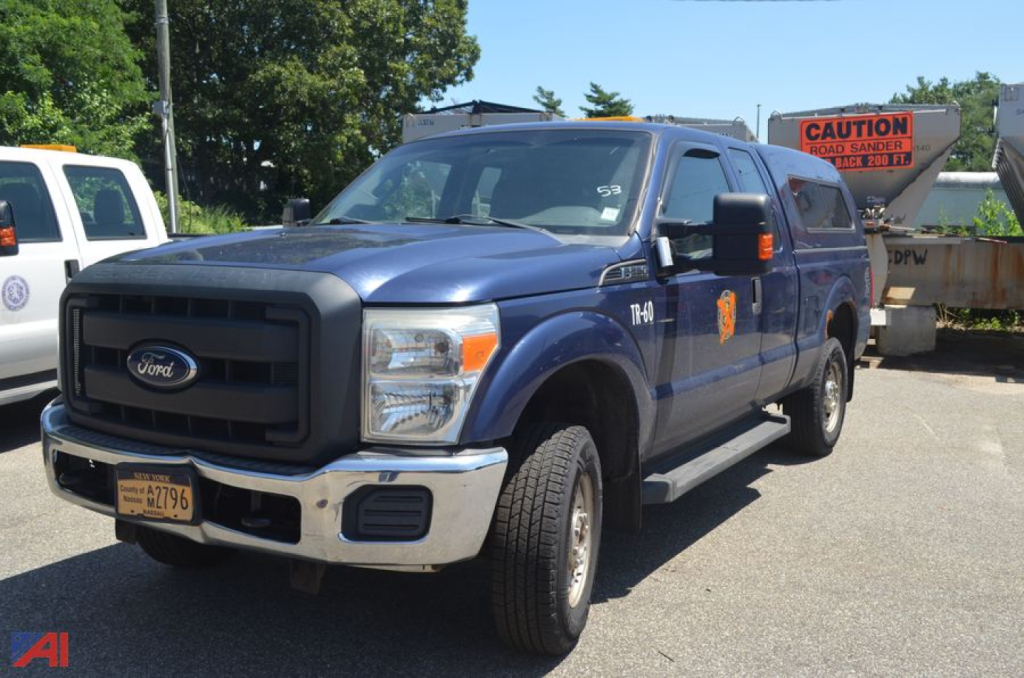 Ford F-250 Super Duty pickup truck in blue, front three-quarter view, with orange decal on door, NY license plate, in a lot.