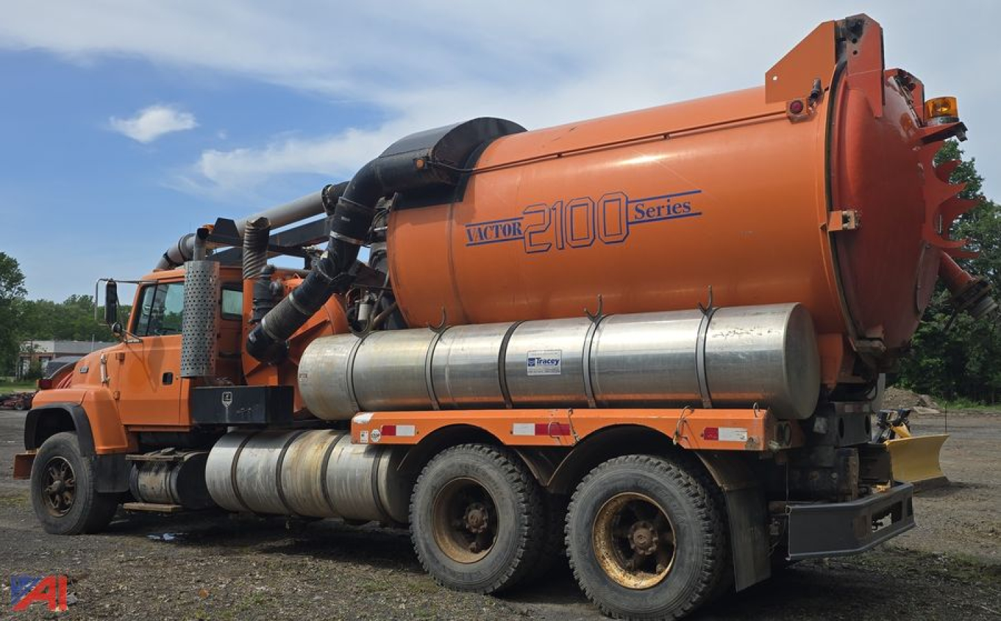Truck vacuum tank unit with orange cab and large orange tank showing 'Vacutank 2100 Series' label and chrome cylindrical tanks beneath.
