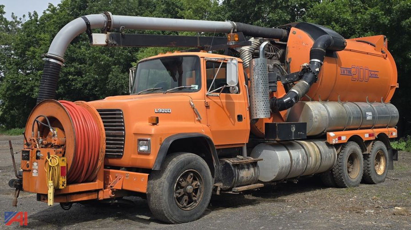 Ford LNT9000 vacuum tank truck with orange cab and Vactor 2100 system, hose reel on front bumper and large exhaust/filtration piping along side.