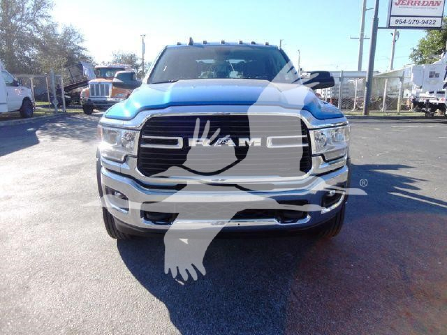 Ram 5500 pickup truck front view with large grille and RAM logo, blue exterior, visible chrome bumper, dealership lot in background.