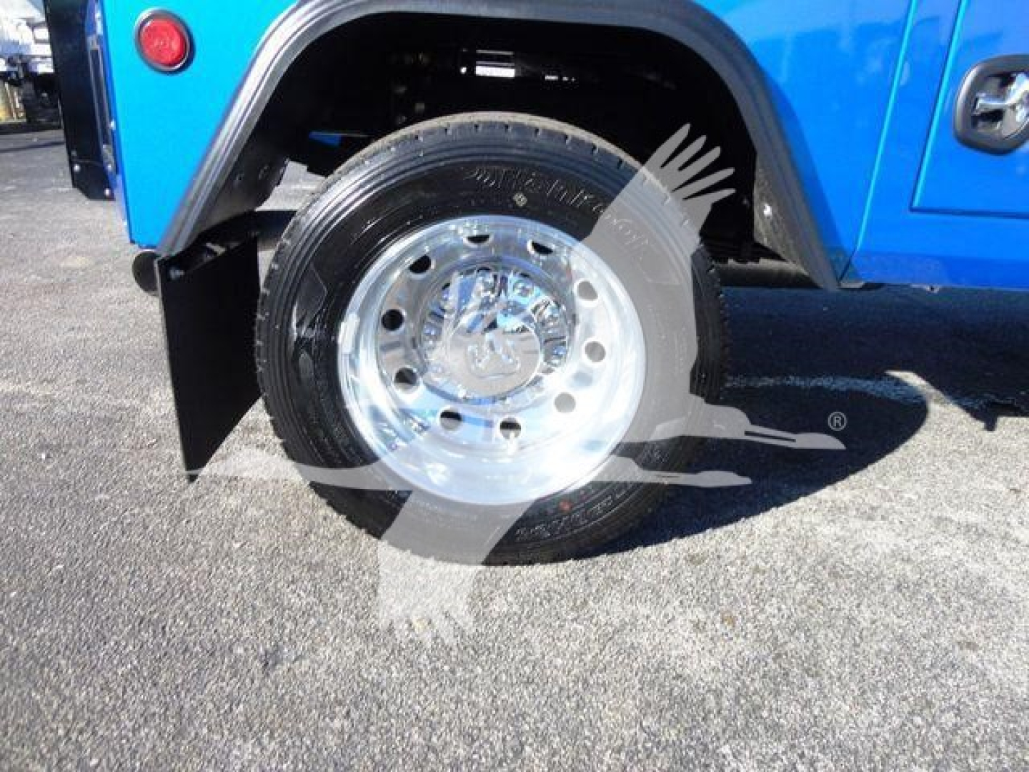 Wheel and front fender of a blue Ram 5500 truck showing polished chrome rim and tire with wheel well and fender flare.