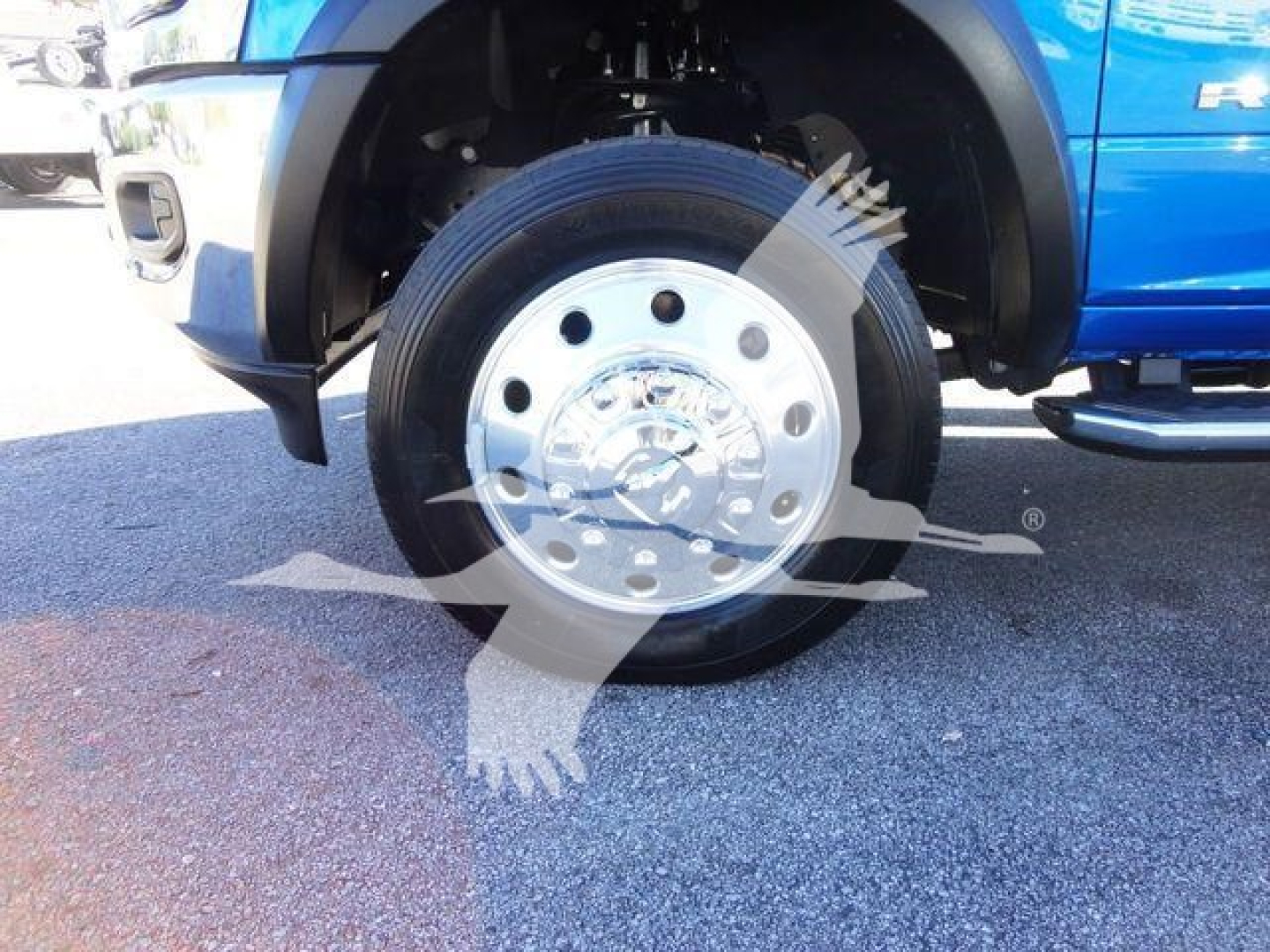 Truck wheel and chrome hubcap on blue Ram 5500 side view showing front tire and wheel well