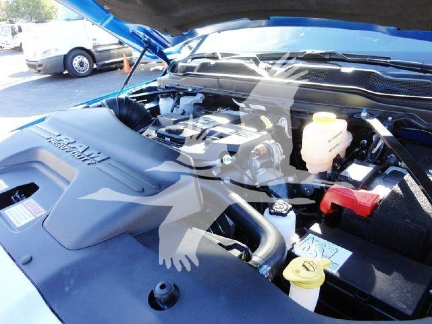 Ram 5500 SLT engine bay with hood open showing engine components, yellow coolant reservoir, red positive battery terminal cover, and various fluid reservoirs.