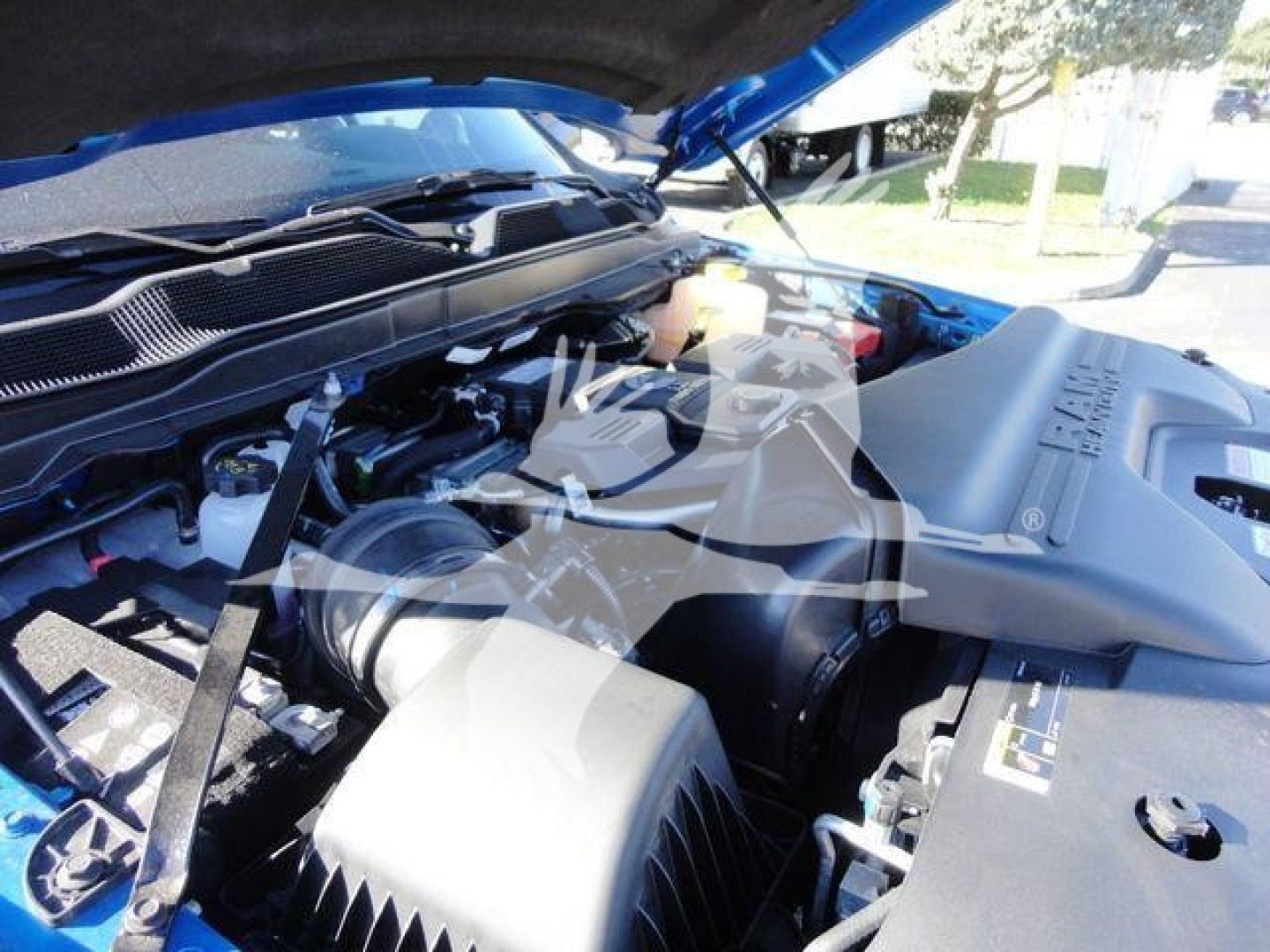 Ram 5500 SLT truck engine bay view with open hood, showcasing engine components and air intake, under-hood wiring, and blue exterior.