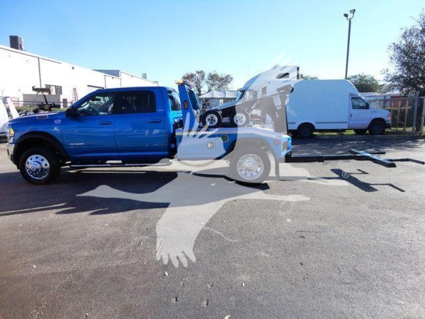 Ram 5500 SLT pickup truck showing blue cab and winch tow truck setup with flatbed trailer equipment in a dealership lot.