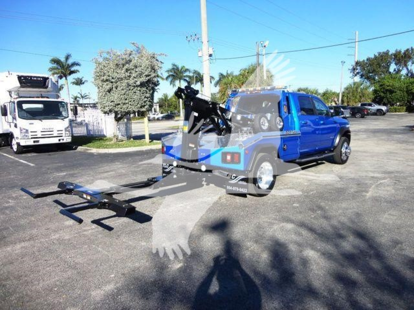 Ram 5500 SLT pickup with mounted winch and tow hitch in a parking lot, branding visible on truck bed and equipment; blue and black vehicle on display.