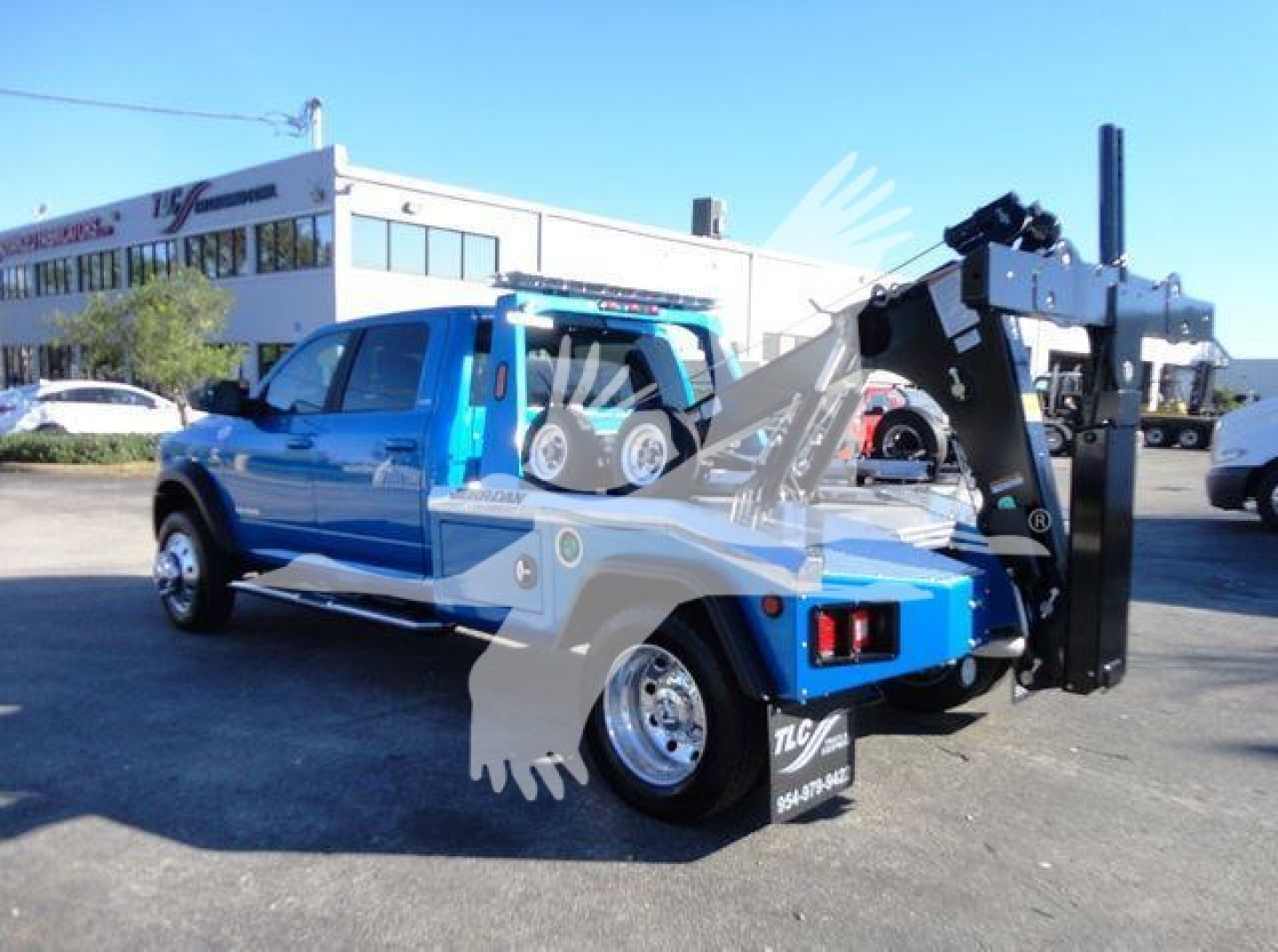 Ram 5500 tow truck with heavy hydraulic winch and boom assembly in blue and black, side view showing winch mechanism and rear hoist.