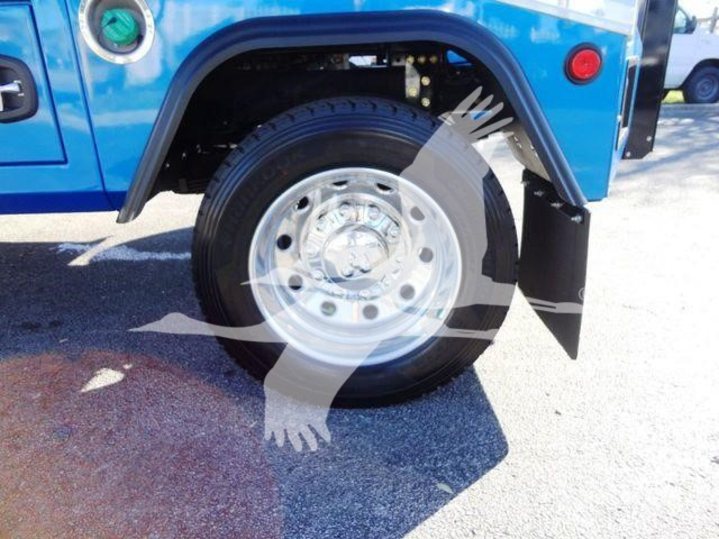 Ram 5500 wheel and fender area showing large silver wheel with black tire, blue truck body, wheel well, and mud flap.