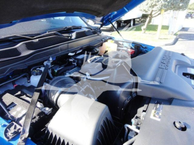 Ram 5500 SLT truck engine bay view with open hood, showcasing engine components and air intake, under-hood wiring, and blue exterior.