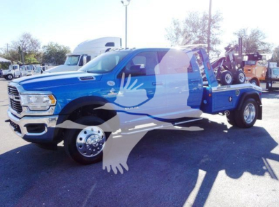 Ram 5500 SLT tow truck, blue cab with flatbed and tow equipment in rear, side view showing dual rear wheels and chrome hubcaps.
