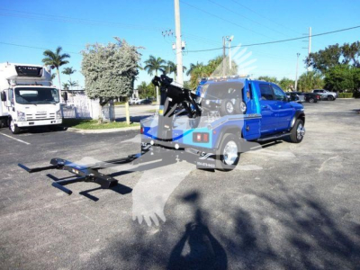 Ram 5500 SLT pickup with mounted winch and tow hitch in a parking lot, branding visible on truck bed and equipment; blue and black vehicle on display.