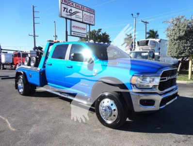 Ram 5500 tow truck with bright blue and gray livery, front grille, dual rear axle, and winch-ready bed clearly visible.