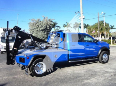2024 Ram 5500 SLT tow truck with blue cab and black equipment rack, truck bed with winch system and rear wheel visible.