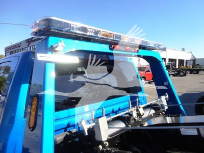 Ram 5500 SLT tow/winch truck rear side showing bright blue cab, rooftop emergency light bar, winch mount and mechanical components.