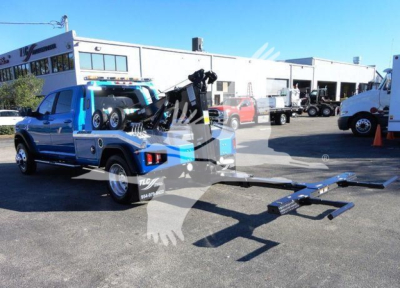 2024 Ram 5500 SLT pickup with winch equipped bed and extended towing ramp, blue vehicle in dealership lot