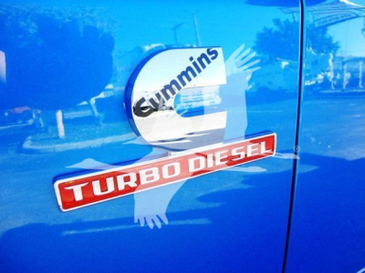Door panel showing Cummins turbo diesel badge and RAM truck emblem on blue pickup side.