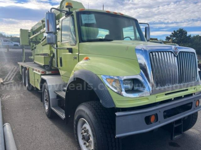 International 7600 truck chassis with lime green paint and equipment mounted on flatbed, front grille and headlamps visible.