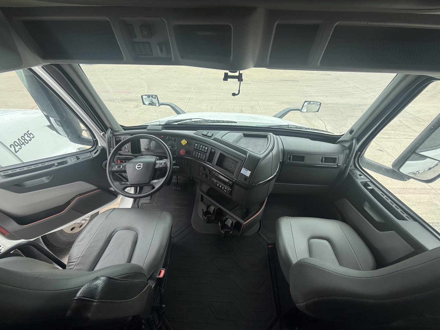 Volvo VNR dashboard and cab interior view with steering wheel, two front seats, and center console in view.