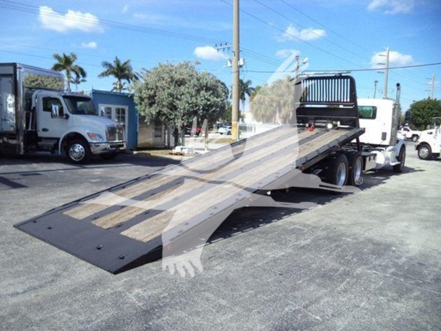 2016 Peterbilt 567 rollback tow truck with ramp bed deployed, metal loading ramp and white cab visible, VIN 1NPCL70XXGD301476 details on listing.