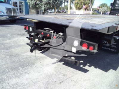 Flatbed rollback show rear of 2016 Peterbilt 567 with hitch, taillights, and hydraulic components visible on flatbed.