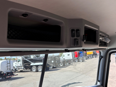 Cab interior overhead control panel and storage compartment of a Mack GR64B roll-off truck showing switches, vents, and dashboard area.