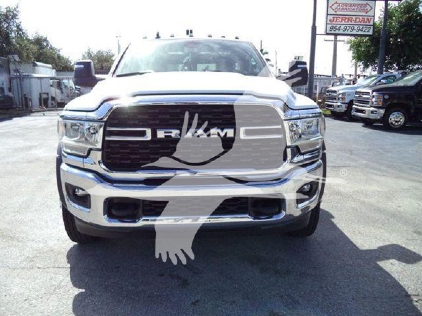 Ram 4500 pickup truck front view showing large grille with RAM letters and bumper, chrome finish, dealership lot in background.