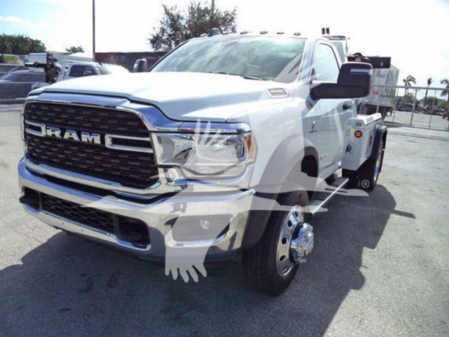 Ram 4500 tow truck front-left view showing chrome grille and dual rear wheels on a white cab with winch equipment in background.