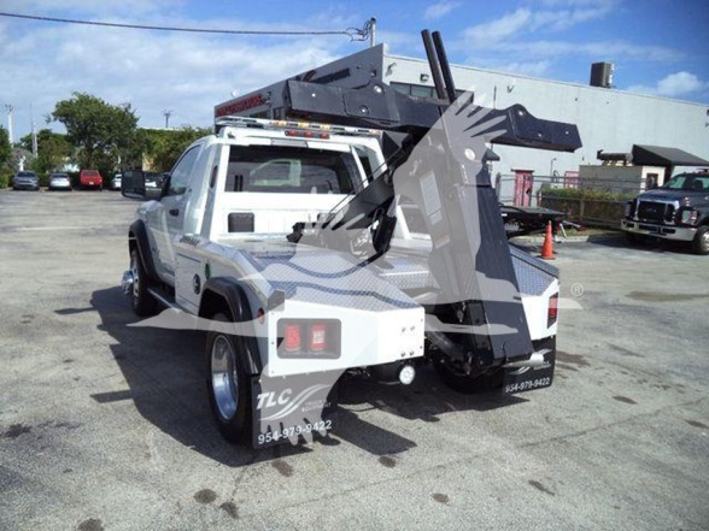 Ram 4500 tow truck rear view showing winch and crane apparatus with white cab and black equipment in a dealership lot.