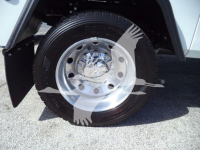 Truck wheel close-up showing tire and chrome hubcap with center emblem and lug nuts.