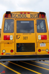 Rear view of a yellow school bus with 'SCHOOL BUS' sign and '327' emergency door number, taillights, and rear bumper visible.