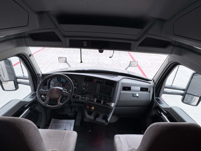 Truck cab interior dashboard of a 2022 Kenworth T680 showing steering wheel, instrument cluster, center console, and passenger seat.