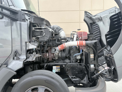 Kenworth T680 engine bay with exposed turbocharger and hoses visible under open hood; radiator and various fluid hoses present.