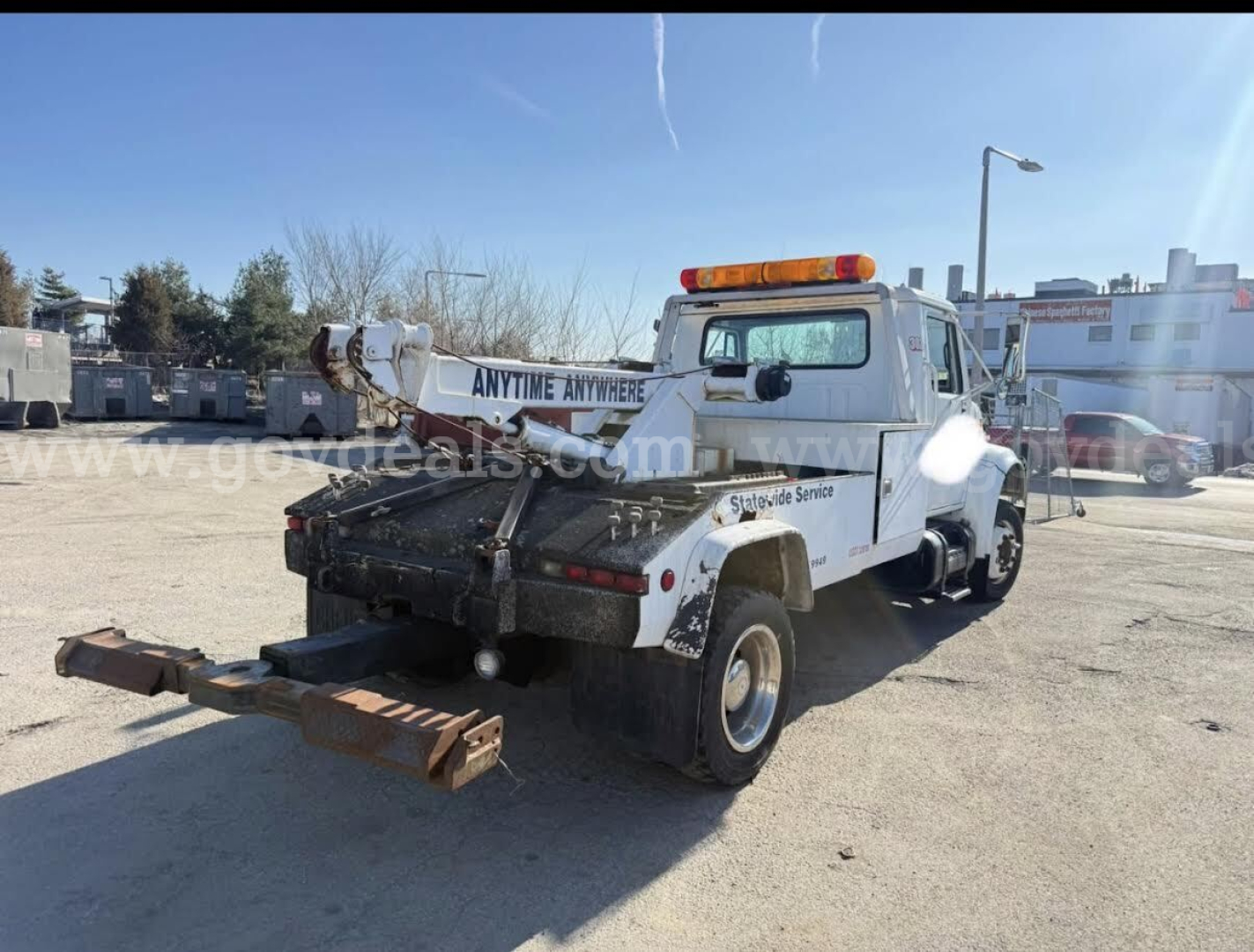 Tow truck from rear-left angle showing heavy hitch and service body with orange beacon lights.